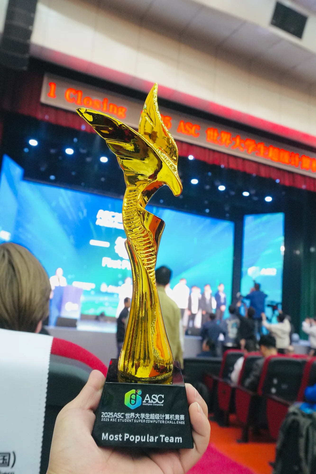 The Most Popular Team trophy held up at the closing ceremony, the stage behind it