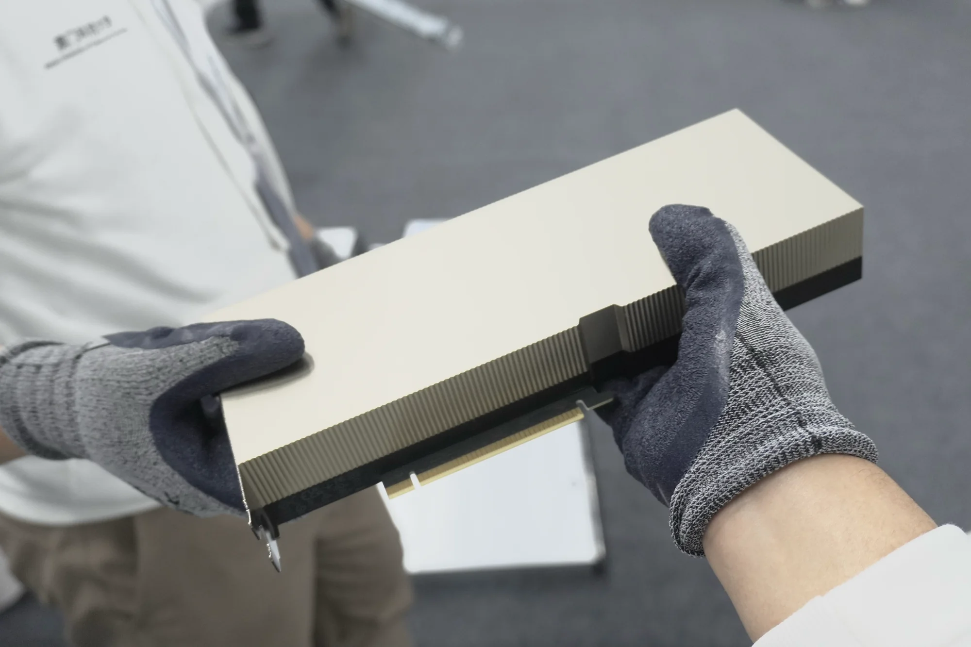 A gloved hand holding a GPU accelerator card that has yet to go into a server