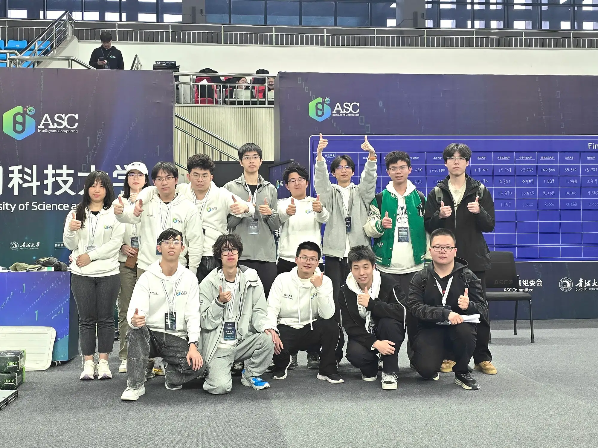 Our team and friends from other teams giving a thumbs-up in front of the live scoreboard