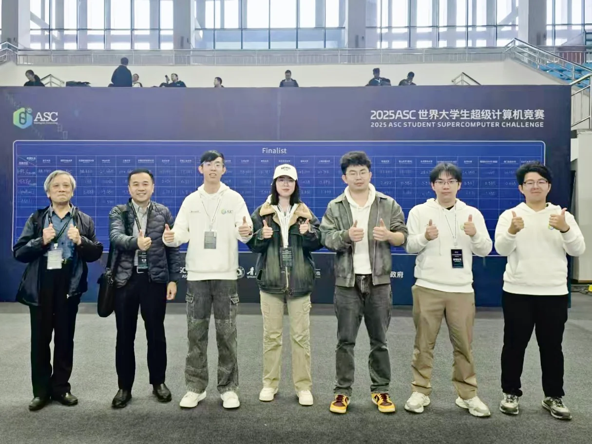 Two faculty members and five teammates giving a thumbs-up in front of the Finalist scoreboard
